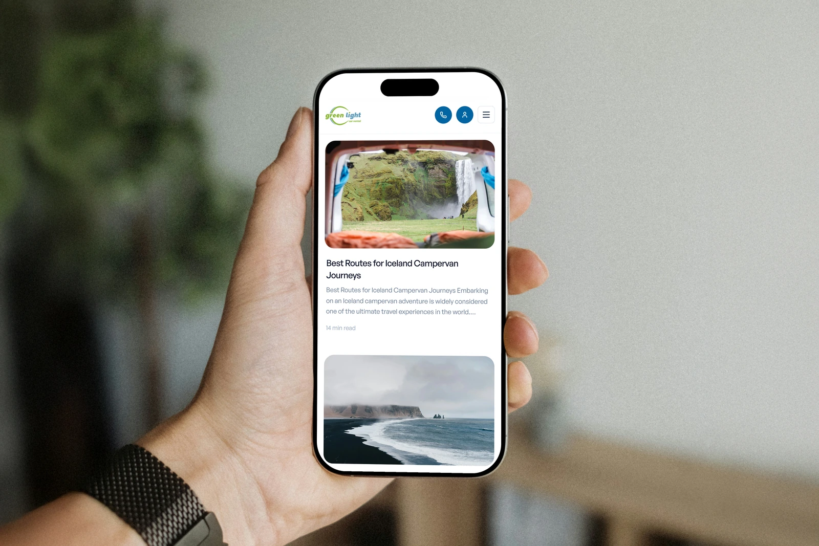 The article card about campervan routes in Iceland displayed on a phone held in a bright home.