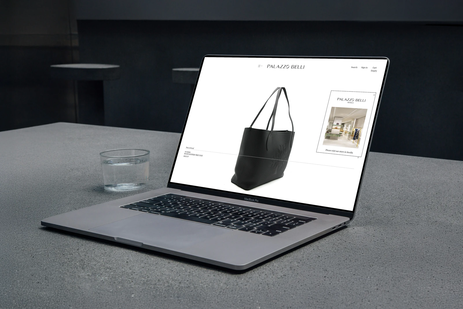 Palazzo Belli luxury fashion website displayed on a MacBook on a concrete countertop in a dark interior.