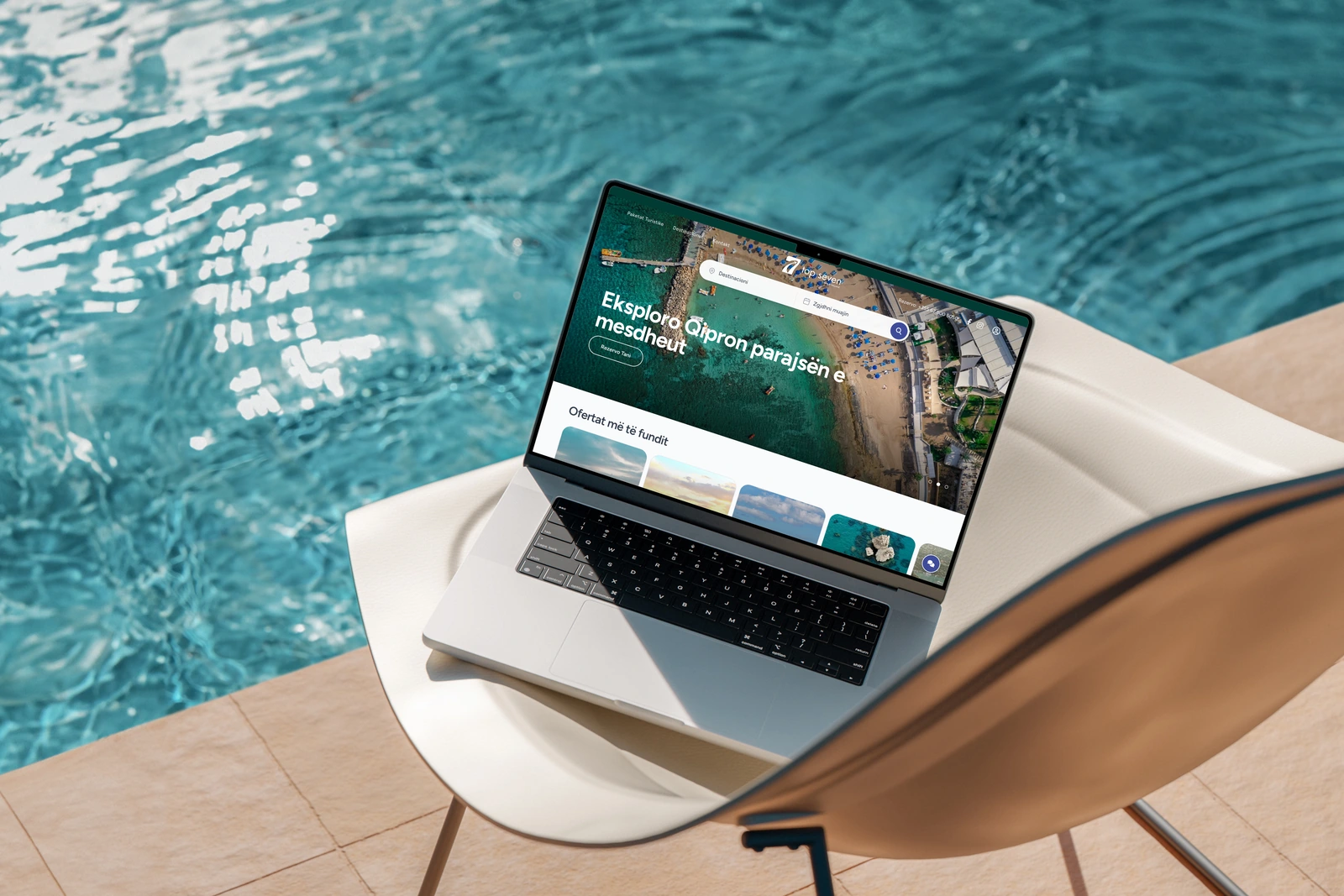 Top Seven Travel website on a MacBook on a lounge chair beside a swimming pool.